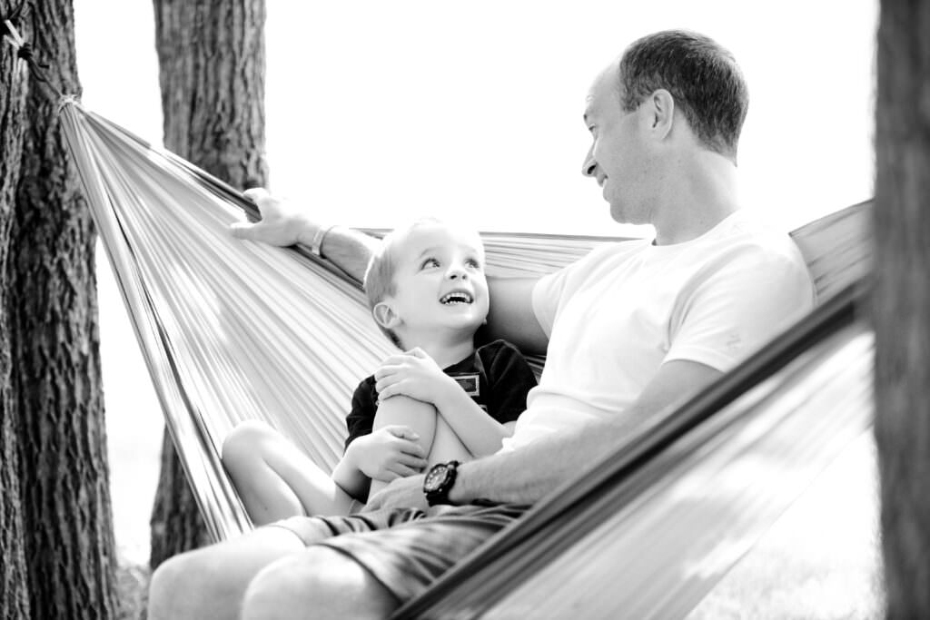 Father and child laughing together in a hammock