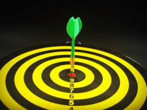 Green dart in the bullseye of a yellow target