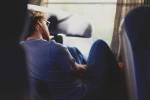 Person sitting alone with head in hands beside a window
