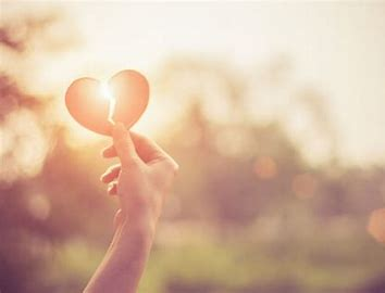 Hand holding a paper heart up to the sunlight