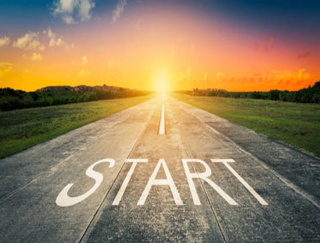 Open road at sunrise with the word START painted on it