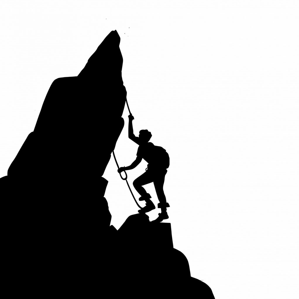 Silhouette of a climber reaching the summit of a rocky peak